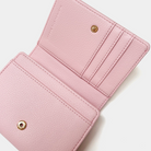 Close-up of a pink wallet with gold accents on a white background