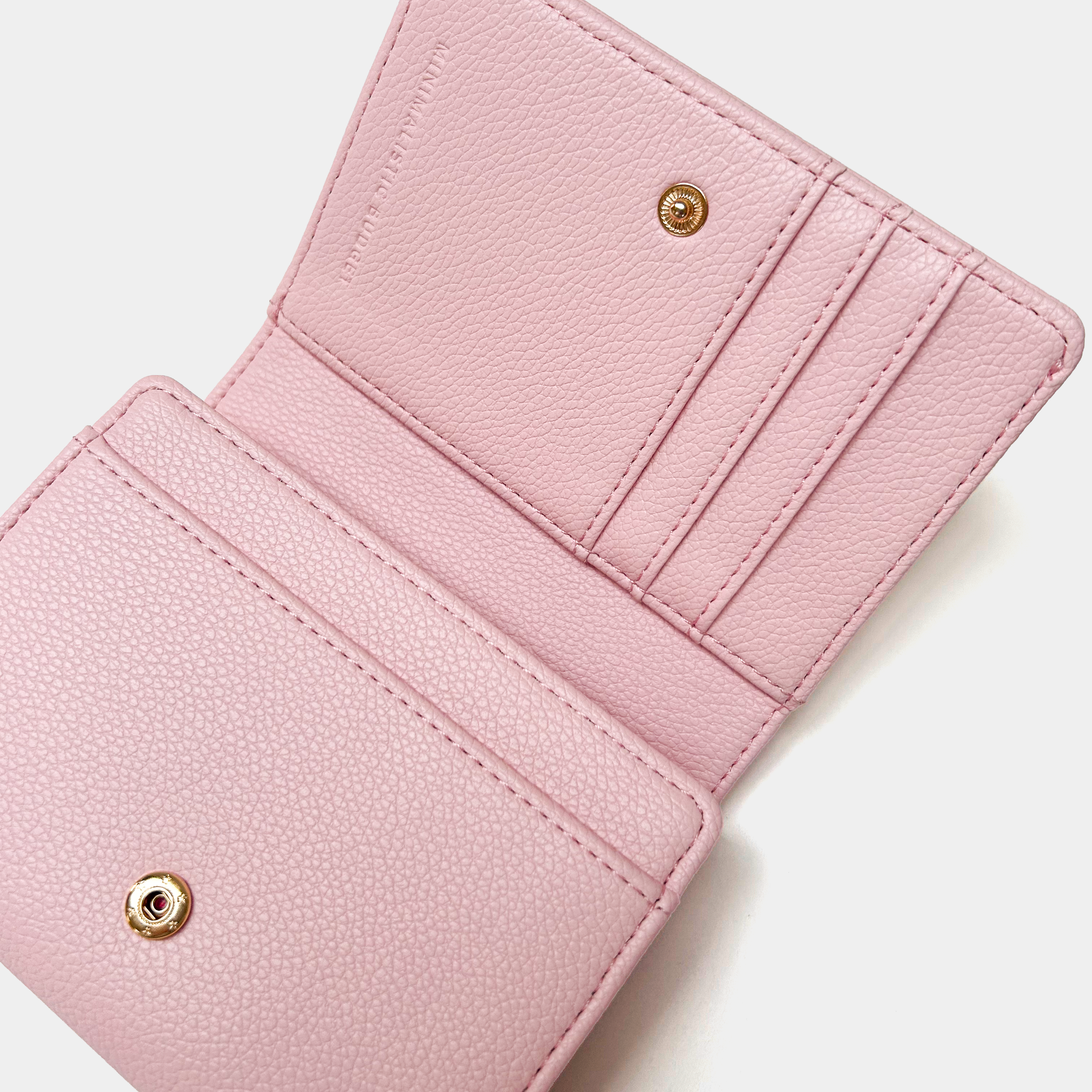Close-up of a pink wallet with gold accents on a white background