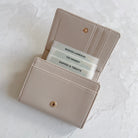 Open beige wallet with card slots on a light gray background