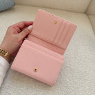 Pink wallet held open by a hand on a light-colored surface